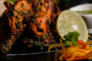Limonlu, yeşil baharatlı soslu ve arka planda kömürlü leziz kızarmış tavuk yakın plan çekimi.