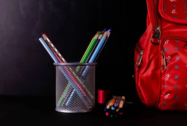 An opened book with a pen stand in the background and blackboard behind -Graduation and classroom concept