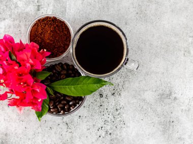 Kahve tozu, siyah americano, çiçek ve yapraklarla kaplı fasulyeler.