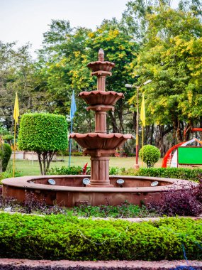 Portre yöneliminde arka planda ağaçlar olan çeşmenin ön çekimi