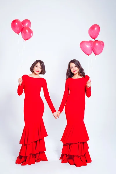 Dos mujeres hermosas jóvenes en un vestido largo rojo con globos — Foto de Stock