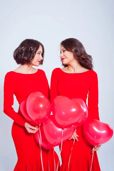 Zwei junge schöne Frauen in einem langen roten Kleid mit Luftballons — Stockfoto