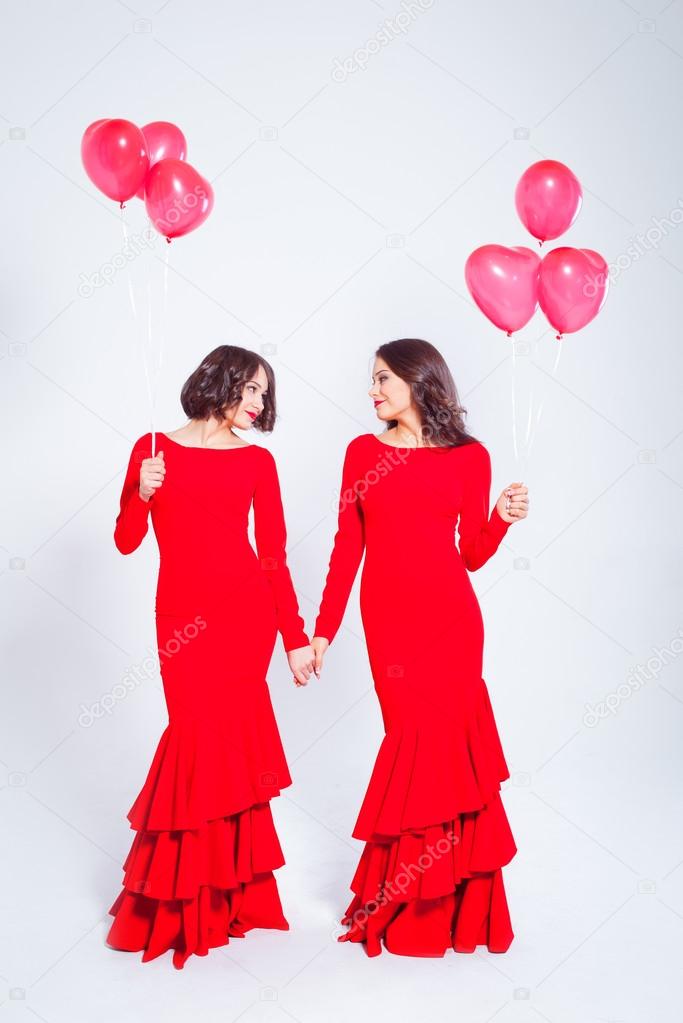 Two young beautiful women in a long red dress with balloons