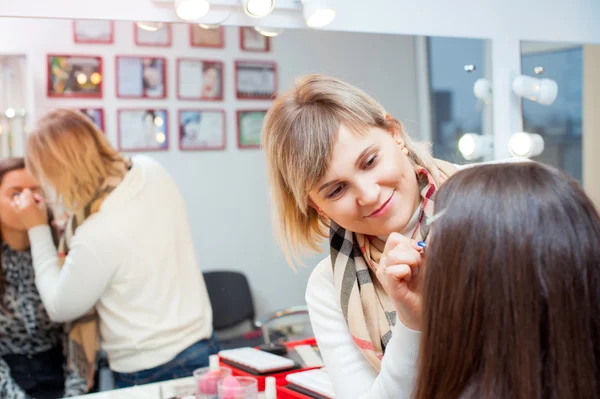 Mujer aplicando maquillaje para una mujer hermosa — Foto de Stock