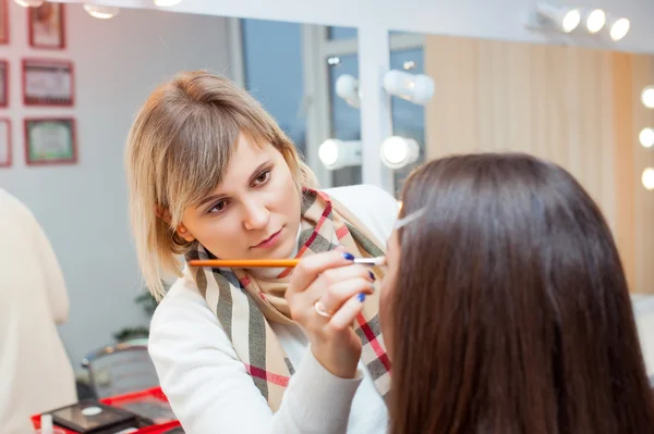 Donna che applica il trucco per una bella donna Immagine Stock