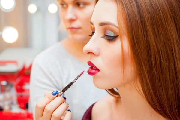 Mujer aplicando maquillaje para una mujer hermosa — Foto de Stock