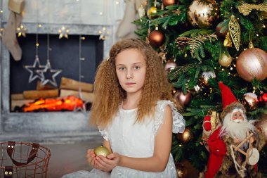 Yeni yıl ve Noel kavramı. Noel 'de şöminenin yanında güzel bir kızın portresi. Noel gecesi, küçük bir kız Noel Baba 'yı bekliyor. Küçük bir kız Noel 'i düşlüyor.