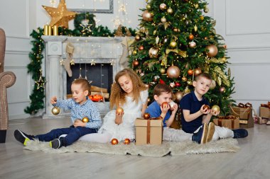 Evdeki Noel ağacının altında bir grup çocuk. Süslü kostümlü kızlar ve erkekler kış tatilini kutluyor. Çocuklar şöminenin yanındaki hediyeleri açın..