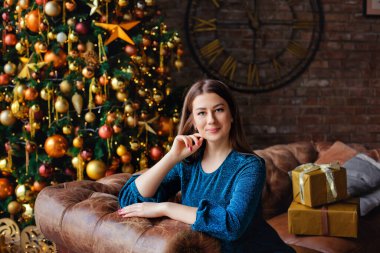 Düz saçlı ve makyajlı güzel bir esmerin portresi. Gece elbisesi giymiş güzel bir kız Noel ışıklarının arkasında poz veriyor. Mutlu Noeller.