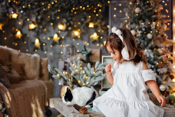 Nettes Kleines Mädchen Mit Einem Hasen Einem Weihnachtlich Dekorierten Raum — Stockfoto