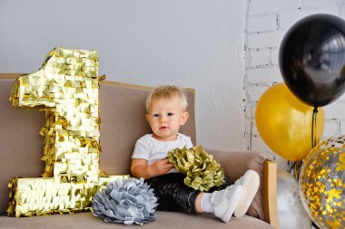 İlk doğum gününde, altın, siyah ve gümüş renkli bir partide tatlı sarışın çocuk..