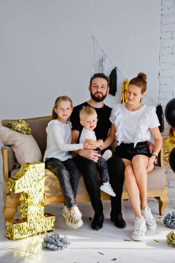 Mutlu bir anne ve babanın portresi kanepeye oturmuş, tatilde aile fotoğrafı çektirmek için poz veriyor. Kameraya bakarken küçük tatlı oğlana ve kızına sarıl.