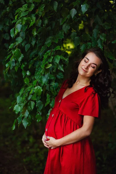 Elinde Çiçekleri Olan Kırmızı Elbiseli Mutlu Hamile Bir Kadın Dinleniyor — Stok fotoğraf