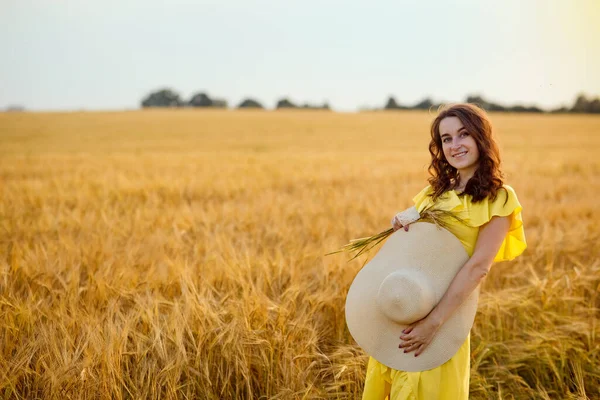 Gün Batımında Altın Buğday Tarlasında Sarı Elbiseli Güzel Bir Genç — Stok fotoğraf