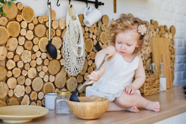 Parlak İskandinav tarzı bir mutfakta küçük bir kız masada oturuyor. Bulaşıklarla, mısır gevrekleriyle, fasulyelerle oynuyorlar. Çocuk gelişimi kavramı Montessori.