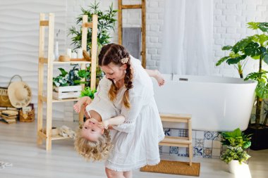 Sevgi dolu bir aile. Bir anne ve küçük kızı oynuyorlar ve sarılıyorlar. Anne kızını kollarında tutuyor ve dönüyor..