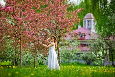 Genç ve çekici bir kadın baharda yeşil bir parkta yürüyor, doğanın tadını çıkarıyor. Sağlıklı, gülümseyen bir kız bahar şafağında döner.