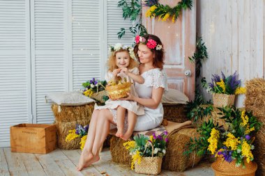 Paskalya kompozisyonu. Beyaz elbiseli ve kafalarında çiçek çelenkleri olan anne ve kız ördek yavrularıyla oynuyorlar. Çiftlik köyü tatili. Çocuklar ve evcil hayvanlar