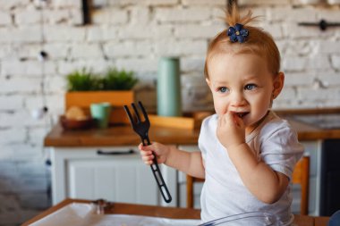 Küçük bir kız mutfak masasında oturuyor. Rahat, gerçek bir hayat ortamında..