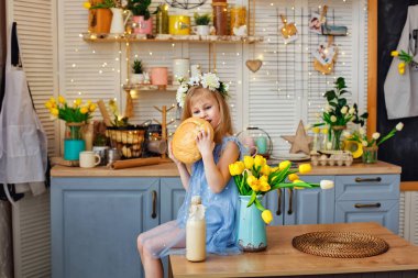 Kız masaya oturur ve bir somun ekmeği ısırır. Masanın üzerinde bir buket sarı lale ve bir şişe süt var..