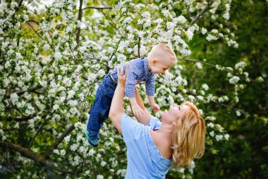 Anne ve oğlu baharda çiçek açan bir elma bahçesinde. Bir kadın bir çocuğu kollarına alır, oynar ve onunla eğlenir..