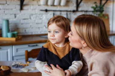 Annesiyle mutfakta komik bir bebek. Büyük bir portre, başka tarafa bakıyor..