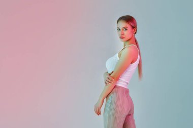 Arka planda açık renk elbiseli genç bir sarışının portresi. Renkli pembe ve mavi neon filtreler kullanılarak çekilmiştir..