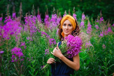 Geniş bir portre, koyu saçlı, ince bir kadın ve tarlada pembe çiçek buketi tutan bir türban. Kirei. Söğüt otlağı. Yosun..