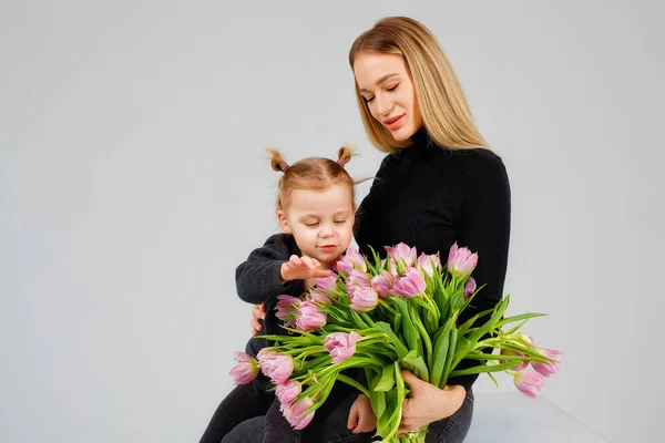 母の日 薄い灰色の背景にピンクのチューリップの大きな花束の母親と女の子が笑顔 家族の休暇と団結 — ストック写真