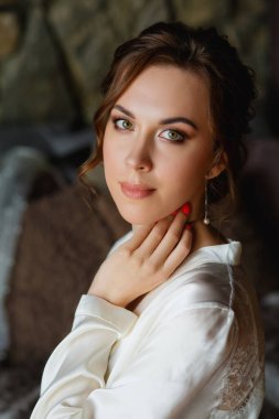 Gelinin sabahı. Muhteşem bir gelin, pencerede beyaz önlüklü güzel bir kadın. Gelinin düğünden önceki sabahı. Doğal güzellik ve profesyonel makyaj..