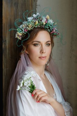 Düğün saç stili ve makyajlı duvağı ve çiçek çelengi olan güzel bir gelinin büyük portresi. Gelinin sabahı.