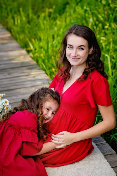 Kızı Yeşil Yaprakların Yanında Kırmızı Elbiseli Hamile Bir Kız Doğada — Stok fotoğraf