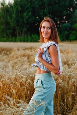 Şık bir genç kadın gün batımında bir buğday tarlasında ağ alışveriş torbası tutuyor. Modern yeniden kullanılabilir mağazalar, sıfır atık kavramı.