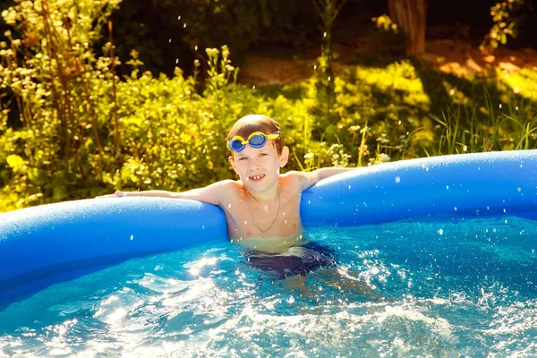 Menino Copos Água Nada Uma Piscina Inflável Jardim Dia Ensolarado — Fotografia de Stock