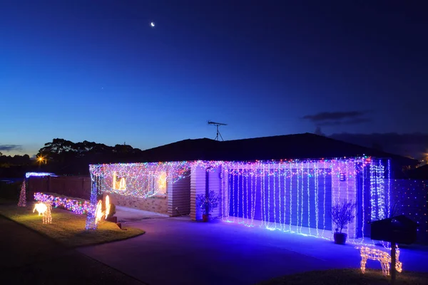 Renkli Noel ışıklarıyla dekore edilmiş bir banliyö evi ve garajı.