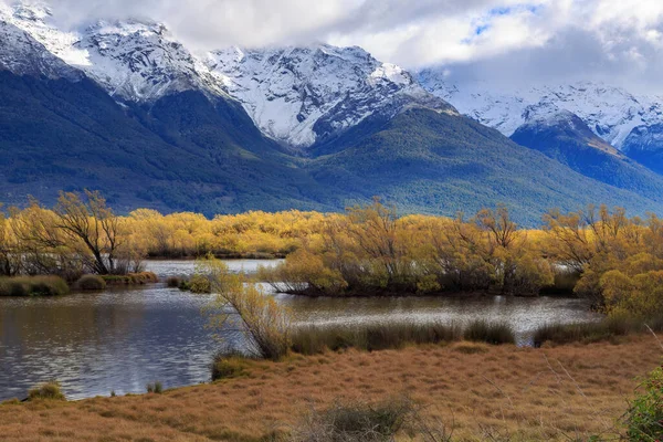 Sonbaharda Yeni Zelanda 'nın Güney Adası' nda söğüt ağaçlarıyla çevrili bir sulak alan olan Glenorchy Gölü. Arka planda Güney Alpleri 'nin dağları var.