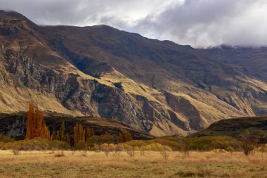 Yeni Zelanda 'nın güneyindeki Wanaka Gölü yakınlarındaki dağlarda sonbahar mevsimi. Fotoğrafın solunda bir çift şelale olan Twin Falls görünüyor. 