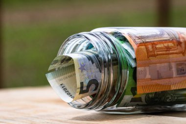 Cam bir kavanozda para biriktirme kompozisyonu. Yatırım yapma ve para tutma kavramı, tecrit edilmiş..