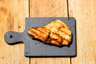 Izgara bifteği, izole edilmiş küçük siyah kesme tahtasına yakın tut. Barbekü, ızgara ve yemek konsepti.