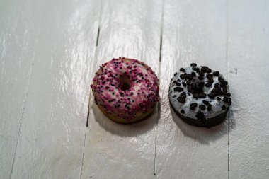 Beyaz ahşap masada renkli çörekler. Şekerli, şekerli, şekerli, şekerli, şekerli. Kopyalama alanı olan üst görünüm