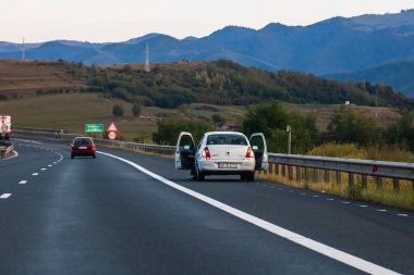 Asfalt yolda tehlikeli ışıkları yanıp sönen, arka manzaralı bir araba. Bükreş, Romanya, 2020