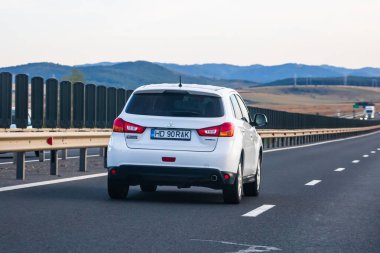 Mitsubishi 'nin arabası asfalt yolda, arka manzaralı caddede ilerliyor. Bükreş, Romanya, 2020