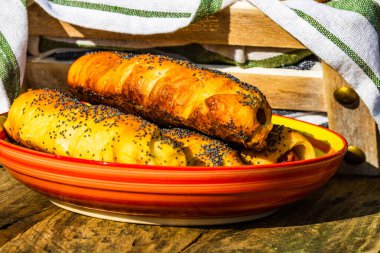 Hamurda pişmiş sosisler tuzlu ve haşhaş tohumları serpiştirilmiş, kırsal bir kompozisyonda. Sosisli börek, lezzetli ev yapımı hamur işleri..