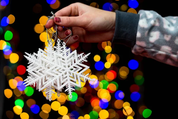 Woman\'s hands hold christmas decoration. Christmas and New Year holidays background, winter season with Christmas ornaments and blurred lights