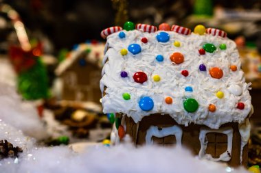 Renkli zencefilli kurabiye evi, bulanık arka planda, Noel süslemesiyle izole edilmiş..
