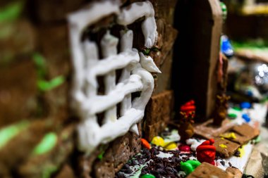 Renkli zencefilli kurabiye evi, bulanık arka planda, Noel süslemesiyle izole edilmiş..