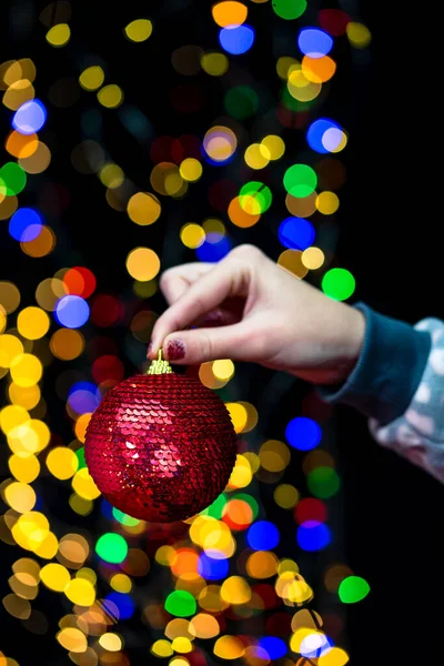 Woman\'s hands hold christmas decoration. Christmas and New Year holidays background, winter season with Christmas ornaments and blurred lights