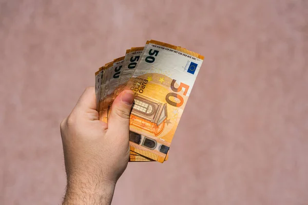 Hand holding and showing a fan of euro money or giving money. World money concept, 50 EURO banknotes EUR currency isolated. Concept of rich business people, saving or spending money.