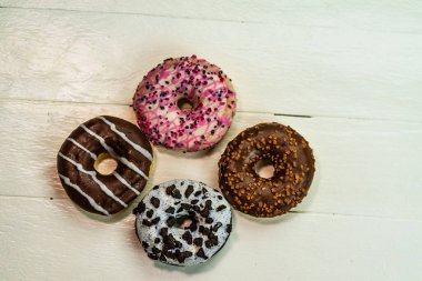 Beyaz ahşap masada renkli çörekler. Şekerli, şekerli, şekerli, şekerli, şekerli. Kopyalama alanı olan üst görünüm