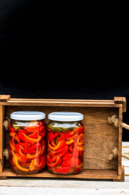 Cam kavanozlu tahta sandık, turşulu kırmızı çan biberi. Konserve gıda konsepti, yalıtılmış konserve sebzeler..